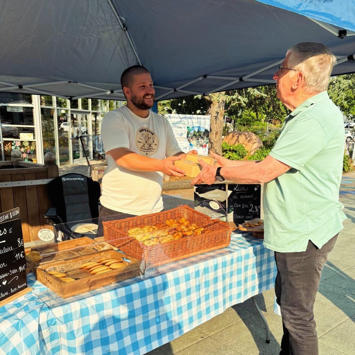 Au stand Madeleine & Léon, une boîte kraft tendue à un client